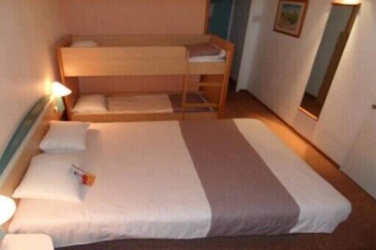 Een eenpersoonskamer met een stapelbed, een nachtkastje met een lamp en een spiegel aan de muur.