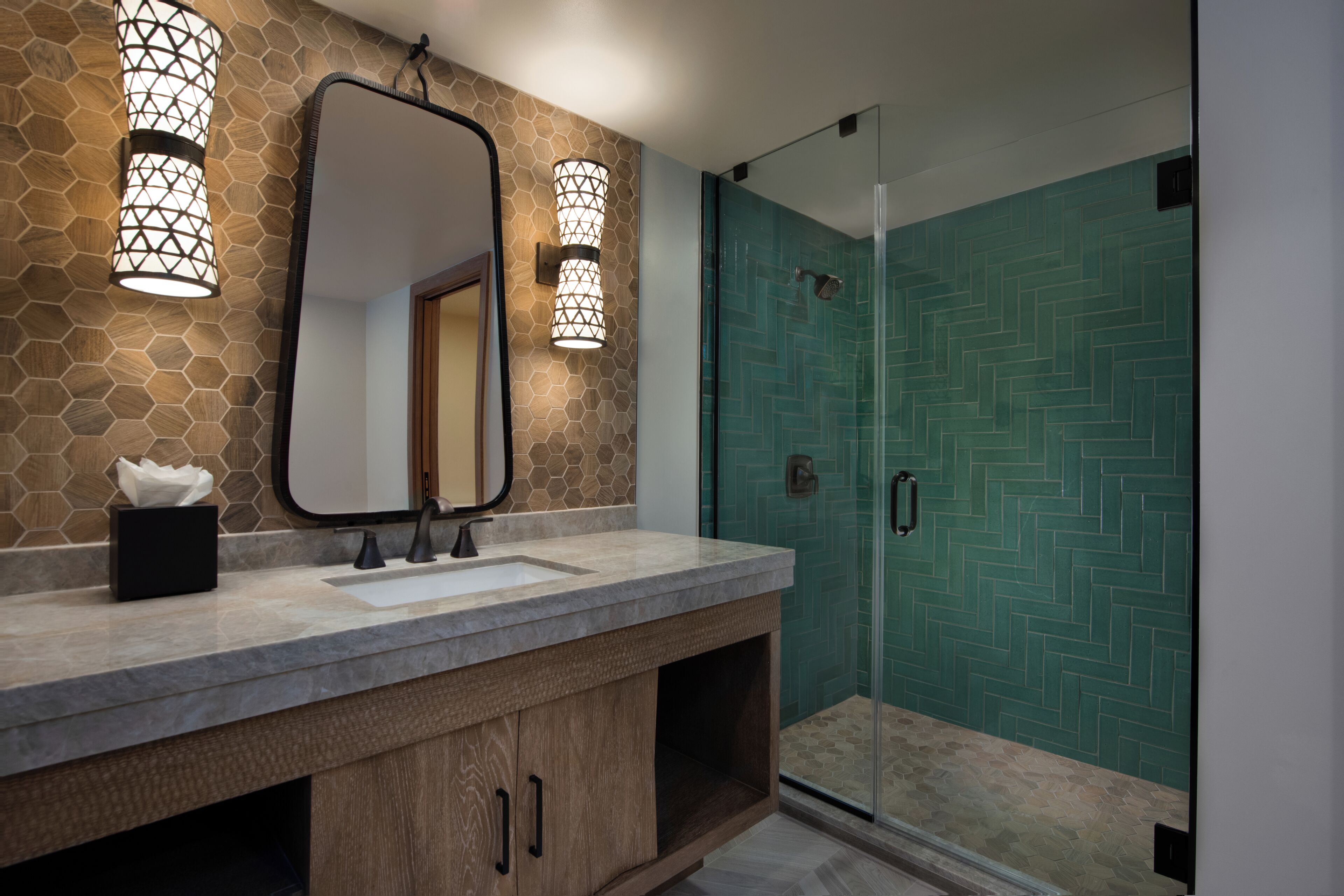 Un bagno con parete effetto pietra, un grande specchio e due luci a parete.