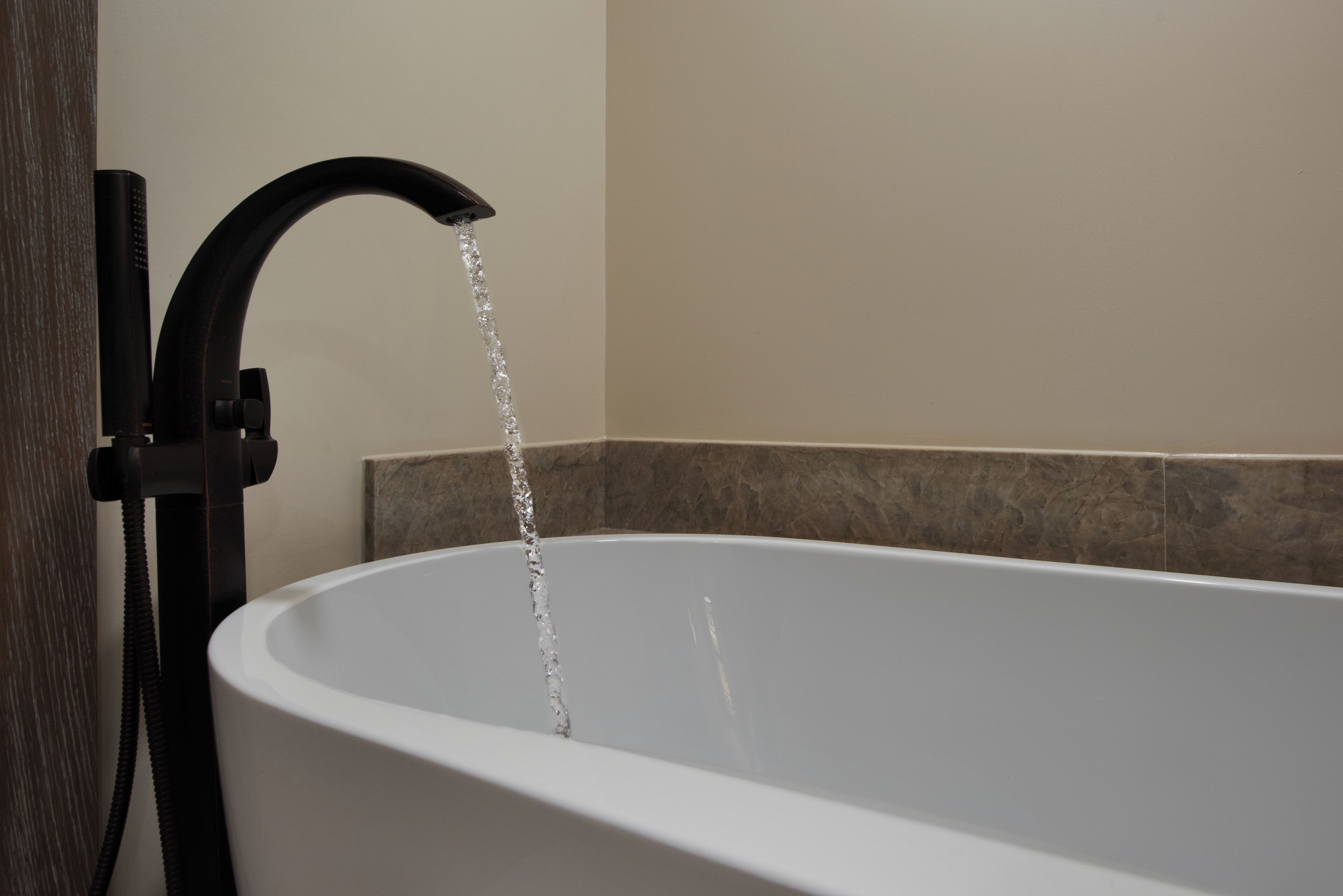 Una bañera con un grifo moderno y un cabezal de ducha, señal de un baño con servicios contemporáneos.