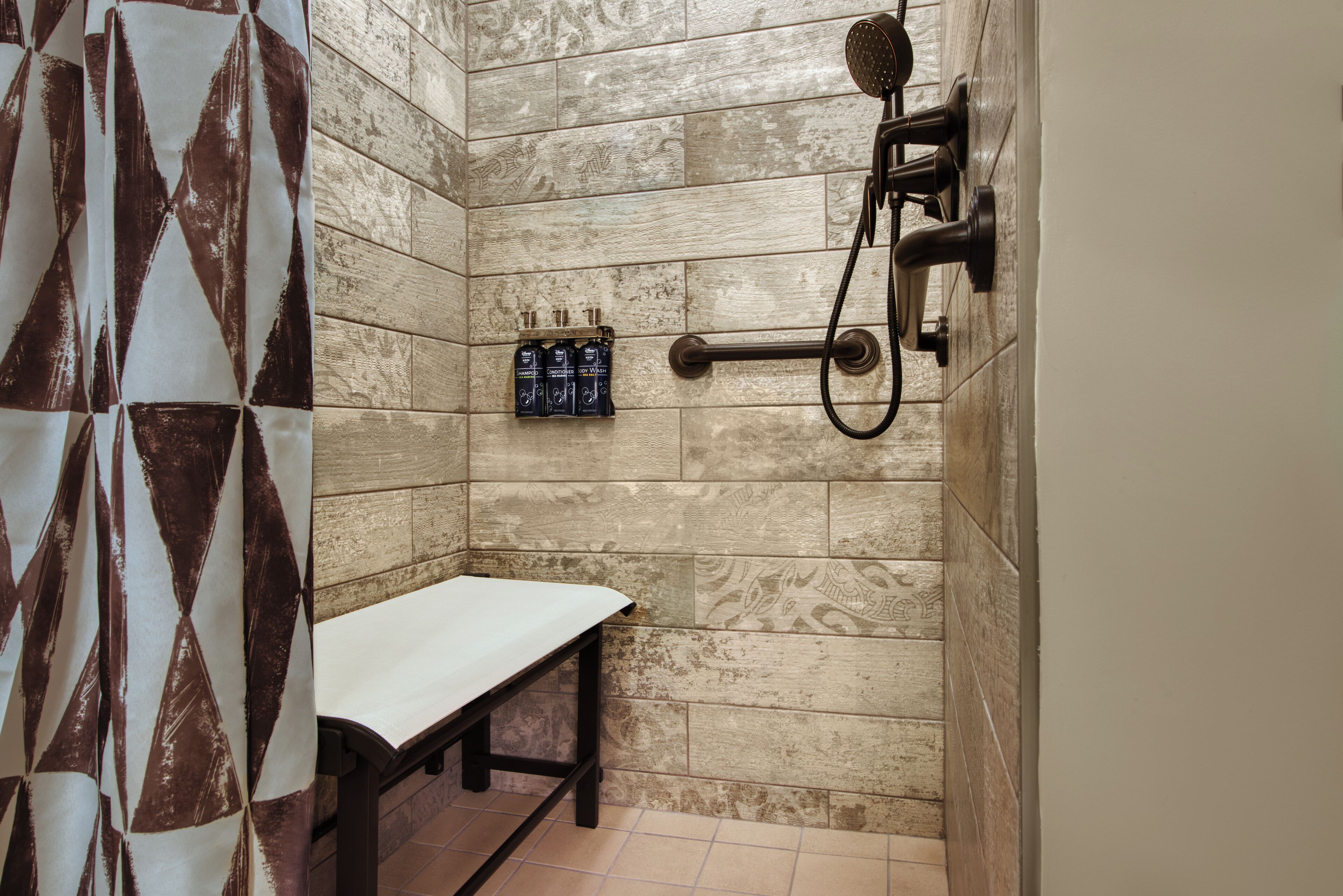 A shower area with a bench, a towel rack, and toiletries on the wall.