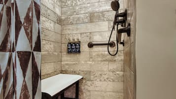 A shower area with a bench, a towel rack, and toiletries on the wall.