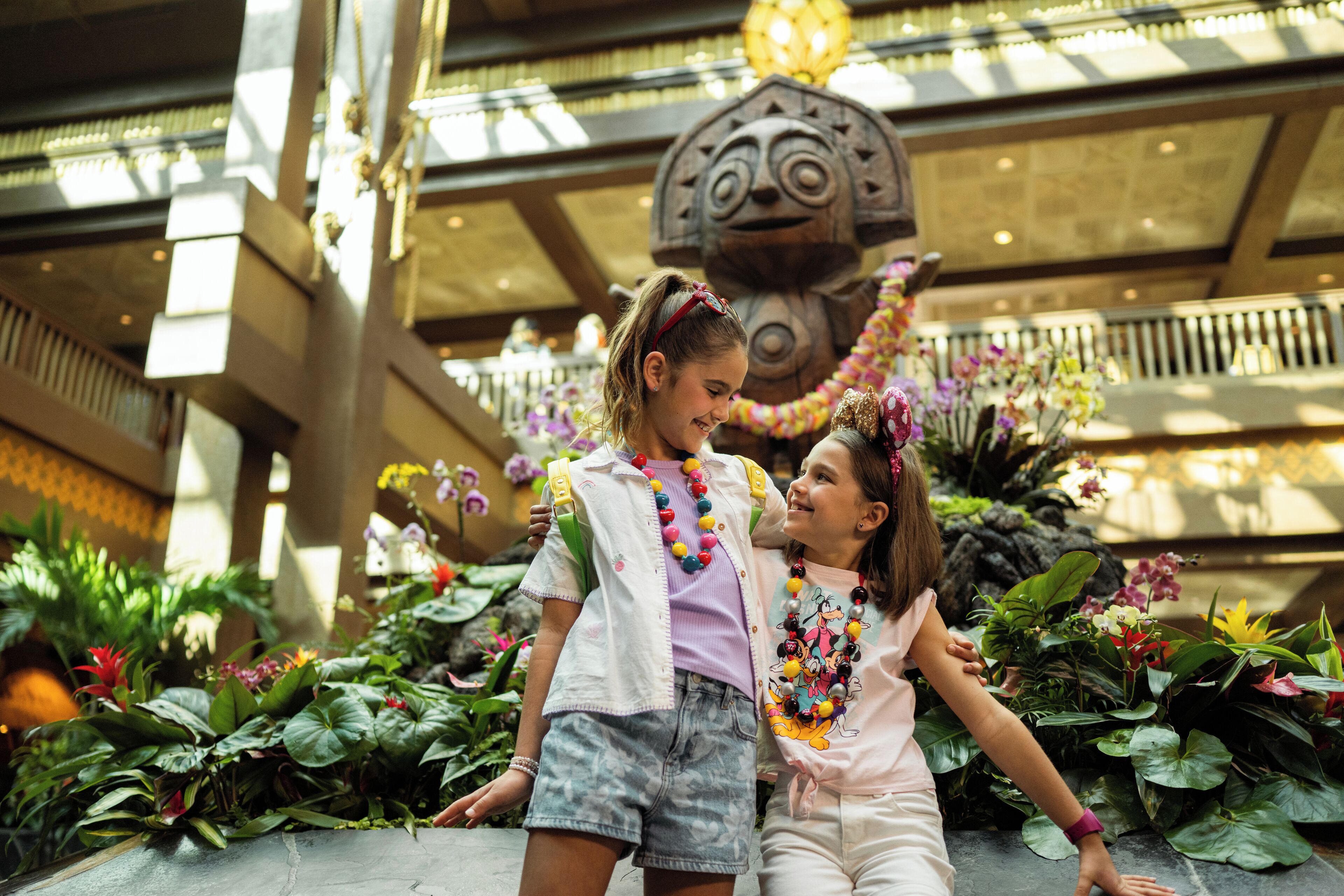 A spacious atrium with a large decorative sculpture, lush greenery, and a modern architectural design.