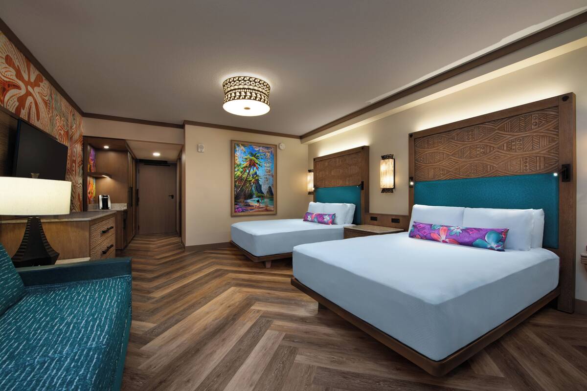 Habitación de hotel con dos camas, televisión, escritorio y un cuadro en la pared.