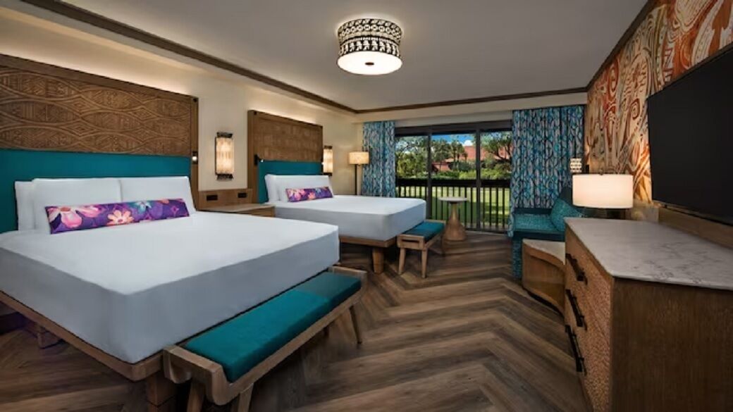 Een hotelkamer met twee bedden, een bureau, een bankje en uitzicht op de omgeving.