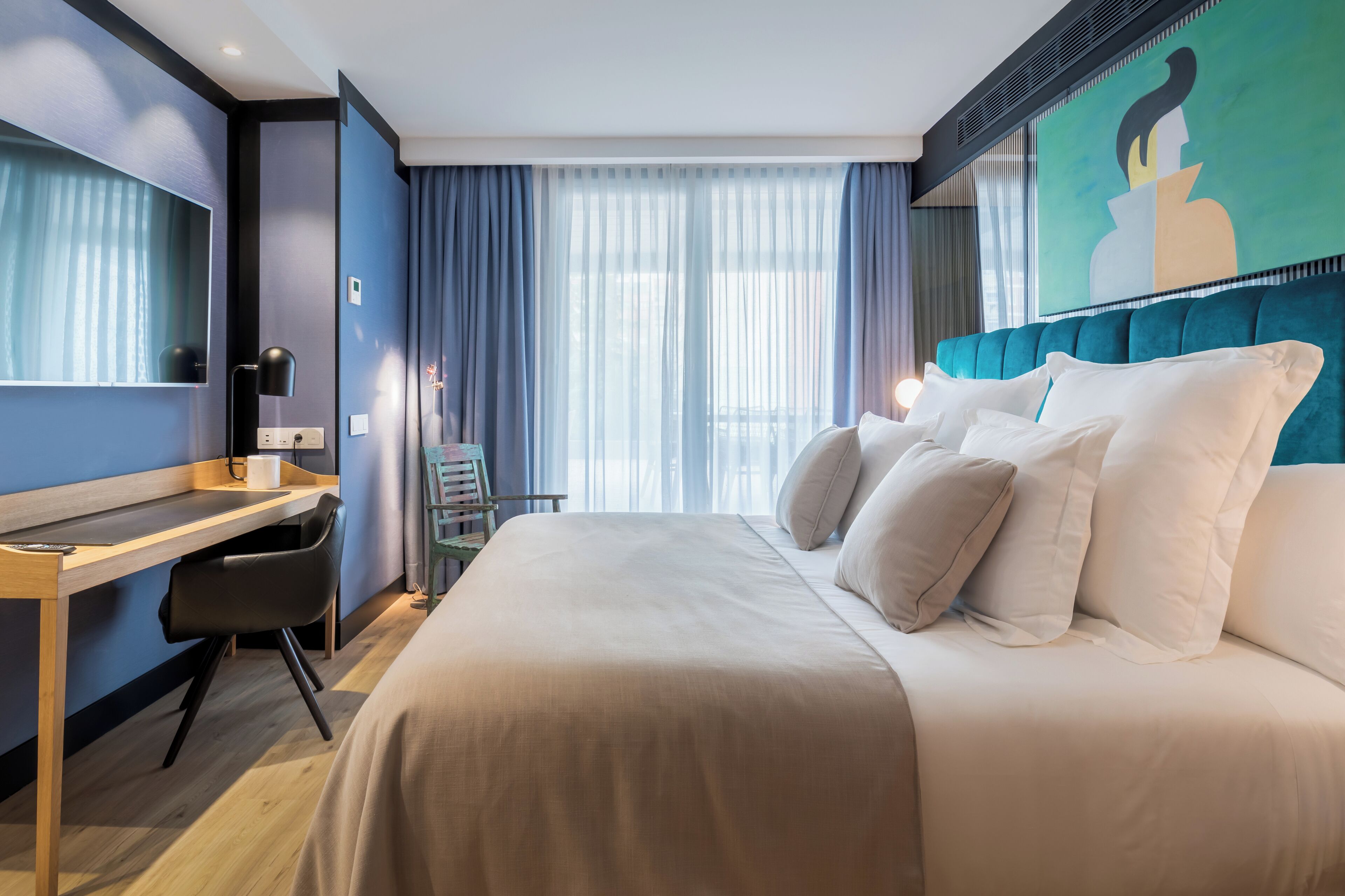 Una habitación de hotel moderna con una cama grande, un escritorio y una silla.