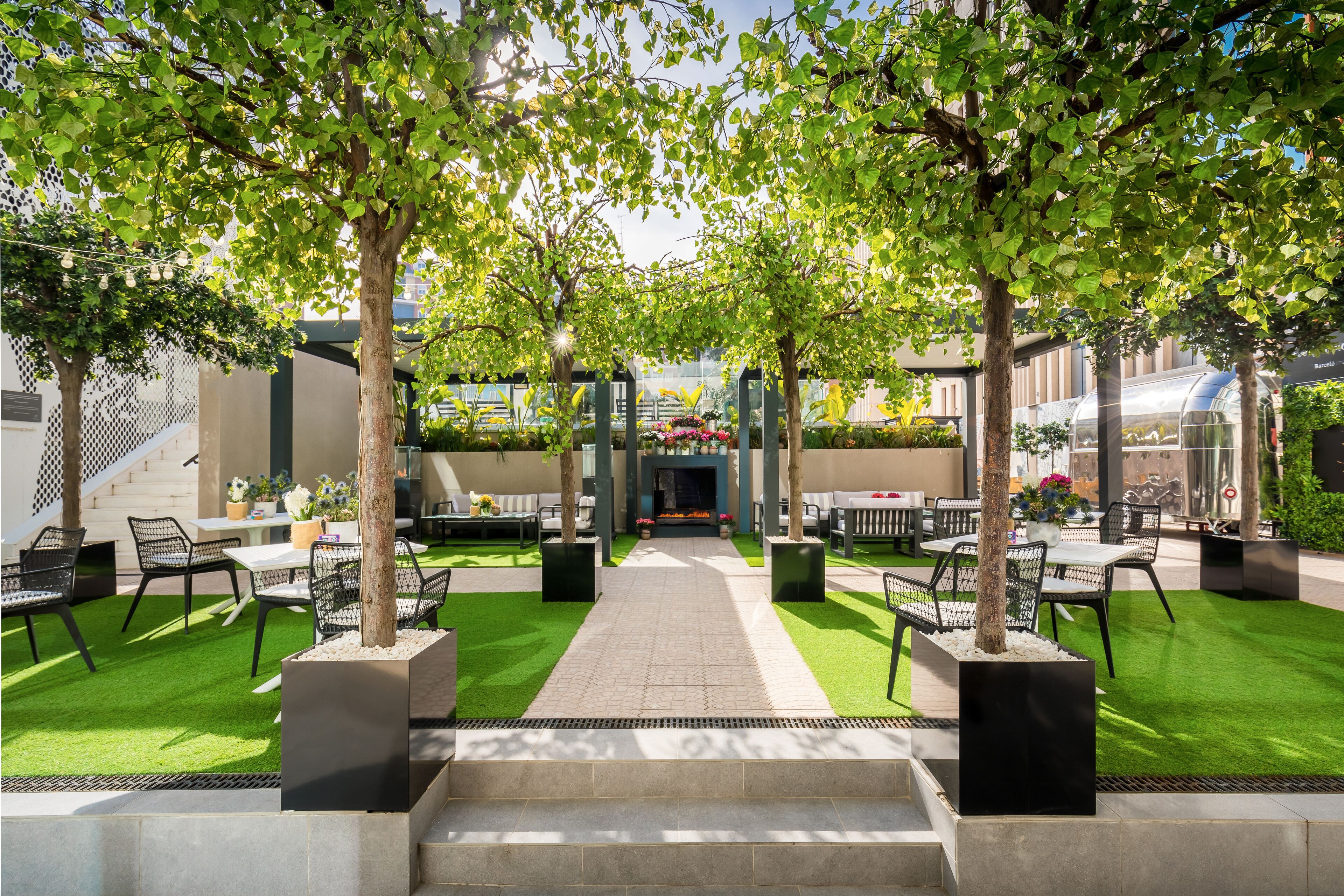 A courtyard with outdoor seating, a fire feature, and a pathway leading to a building entrance.