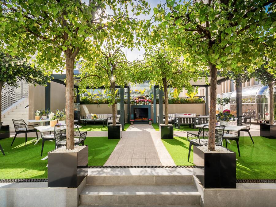A courtyard with outdoor seating, a fire feature, and a pathway leading to a building entrance.