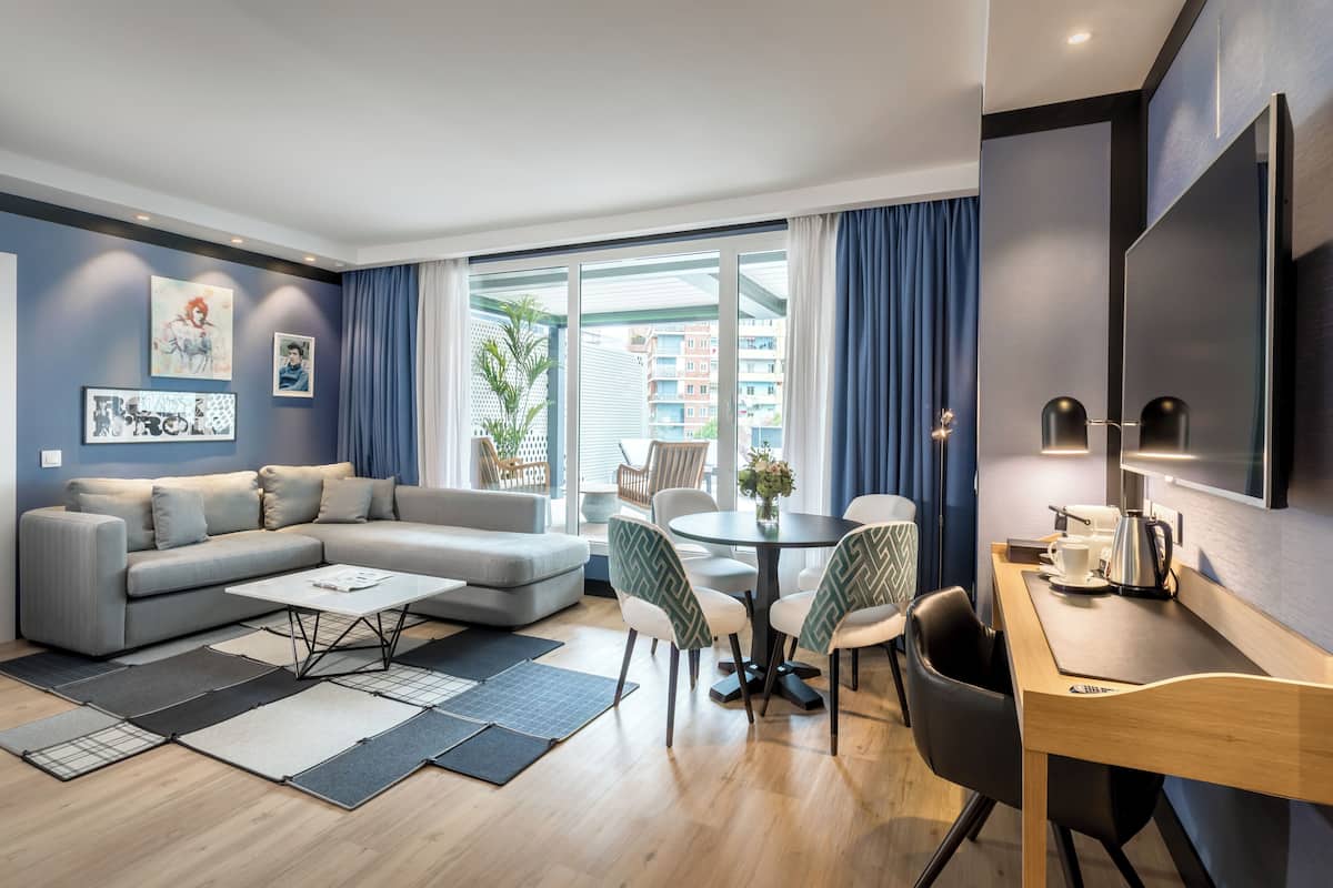 A modern living room with a sofa, coffee table, dining table, chairs, and a TV.