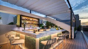 A modern outdoor bar area with a tiled backsplash, bar stools, and a variety of bottles. - Barceló Imagine (Madrid)