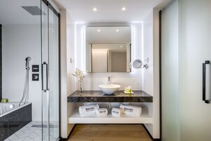 Un baño moderno con ducha de vidrio, lavamanos blanco y encimera de mármol.