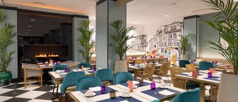 A modern restaurant with checkered flooring, teal chairs, and a fireplace.