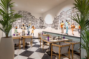 A restaurant with a checkered floor, black and white patterned chairs, and a mural of musicians on the wall.