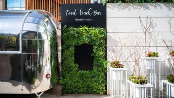 Un bar itinerante chiamato Barceló Imagine, con una parete verde e vasi bianchi.