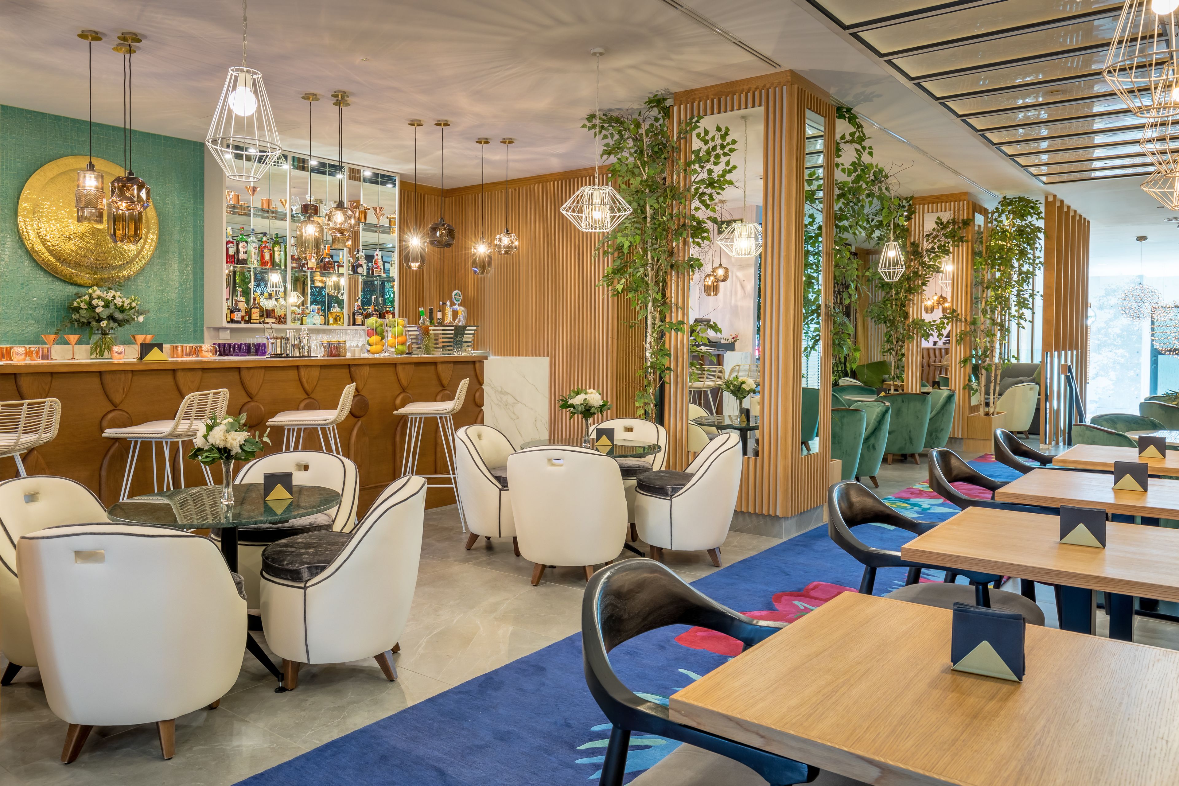 Ein modernes Restaurant mit Barbereich, Sitzgelegenheiten und dekorativen Pflanzen.