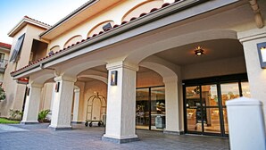 Hotellin sisäänkäynti, jossa on katettu terassi, pylväät ja lasiovi, joka johtaa sisätiloihin.