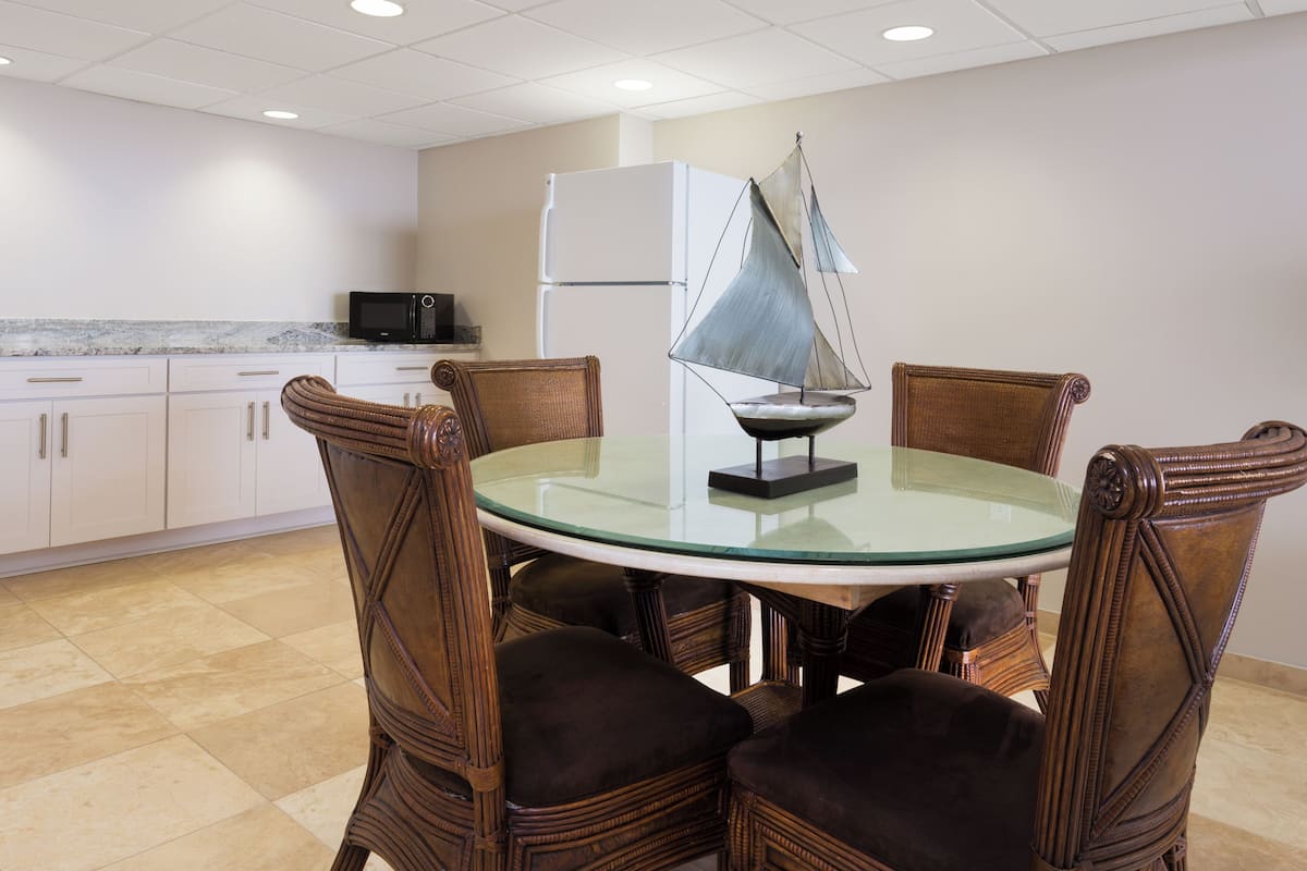 A round glass table with a sailboat model in the center, surrounded by wicker chairs.