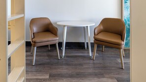 Dos sillones de cuero marrón y una mesa blanca en una habitación con suelo de madera y pared blanca.
