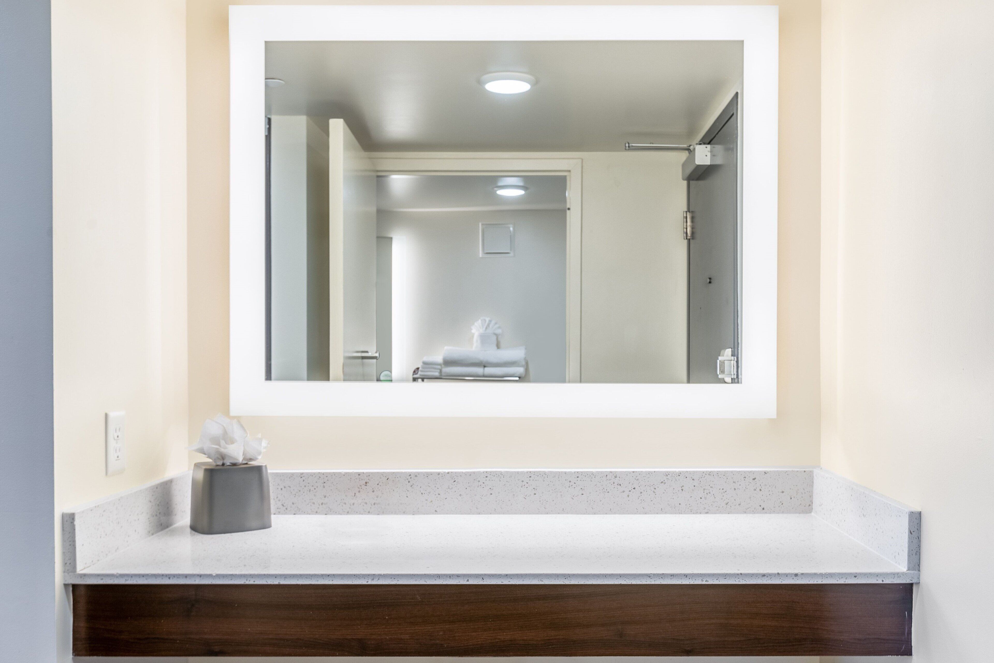 A bathroom with a mirror, a towel rack, and a tissue box on the counter.
