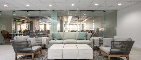 A modern lobby with a sectional sofa, two armchairs, a coffee table, and a patterned rug.