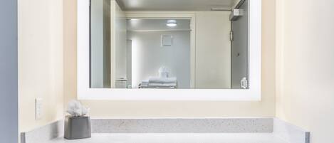A bathroom with a large mirror, a towel rack, and a tissue box on the counter.