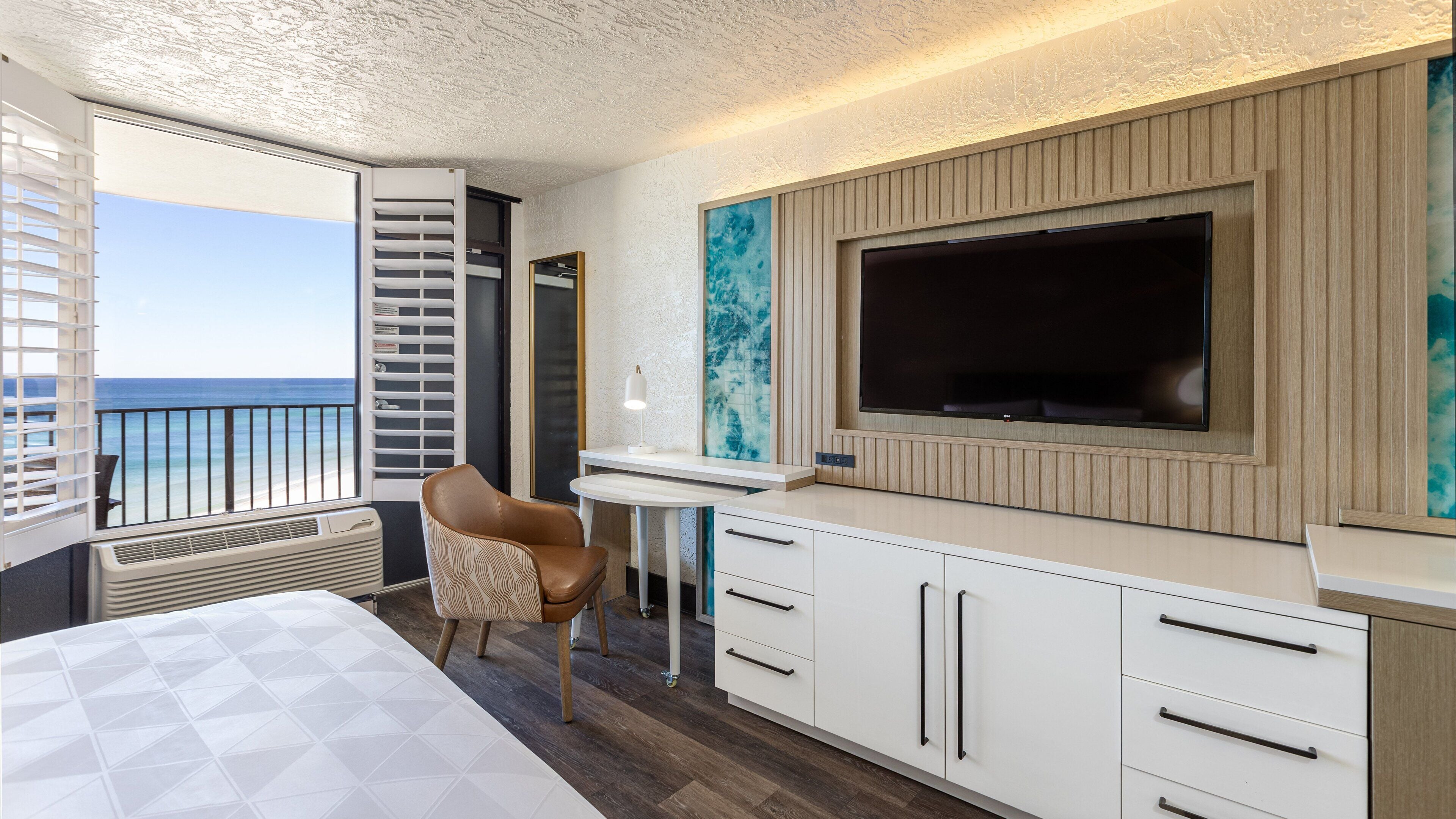 Ein modernes Hotelzimmer mit großem Fernseher, Schreibtisch und Stuhl.