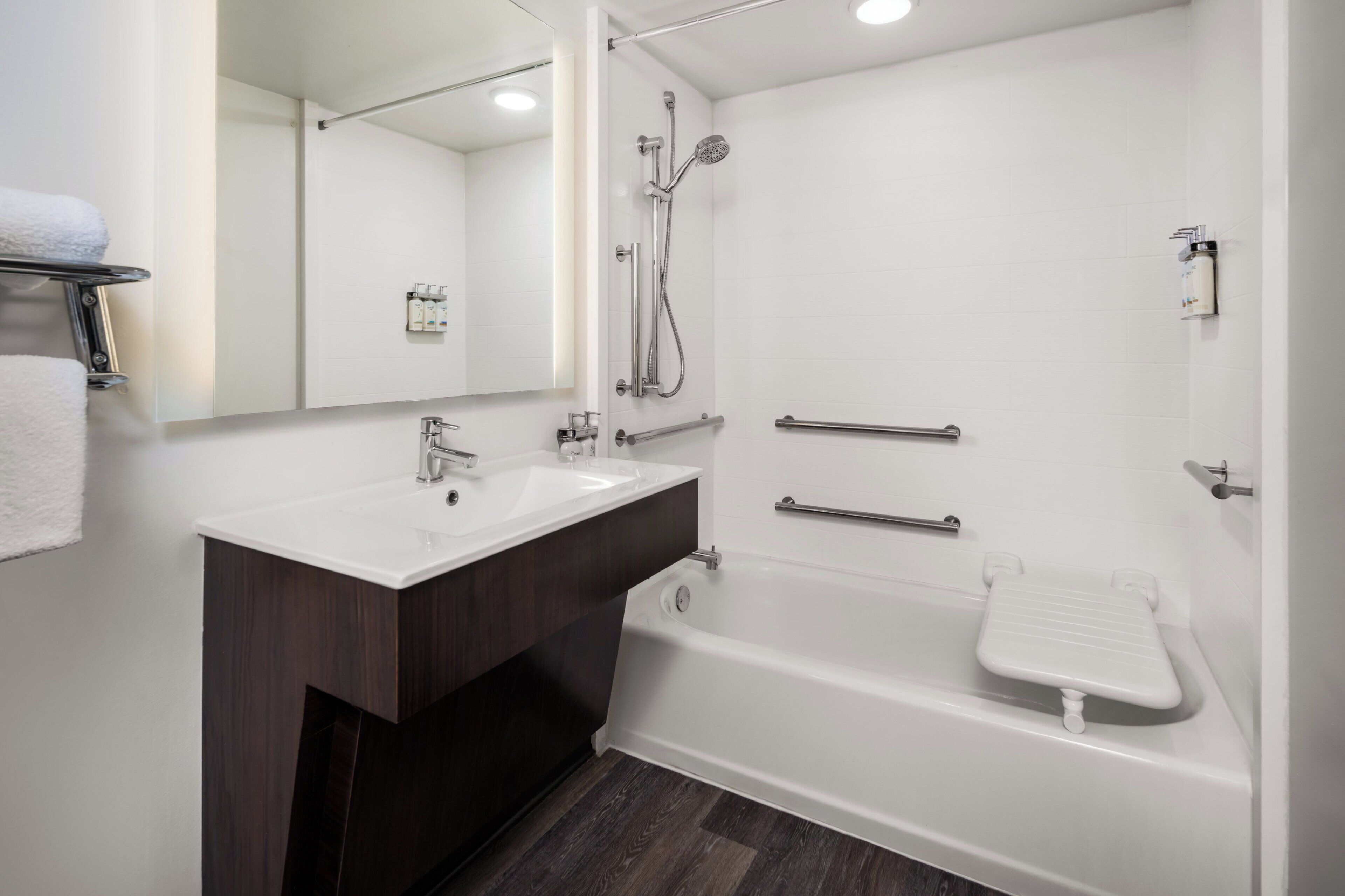 A modern bathroom with a white sink, vanity, and bathtub.