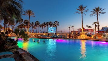 Relax by the pool surrounded by palm trees and lounge chairs.