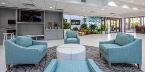 Een moderne zithoek met blauwgroene fauteuils, een salontafel en een televisiescherm.