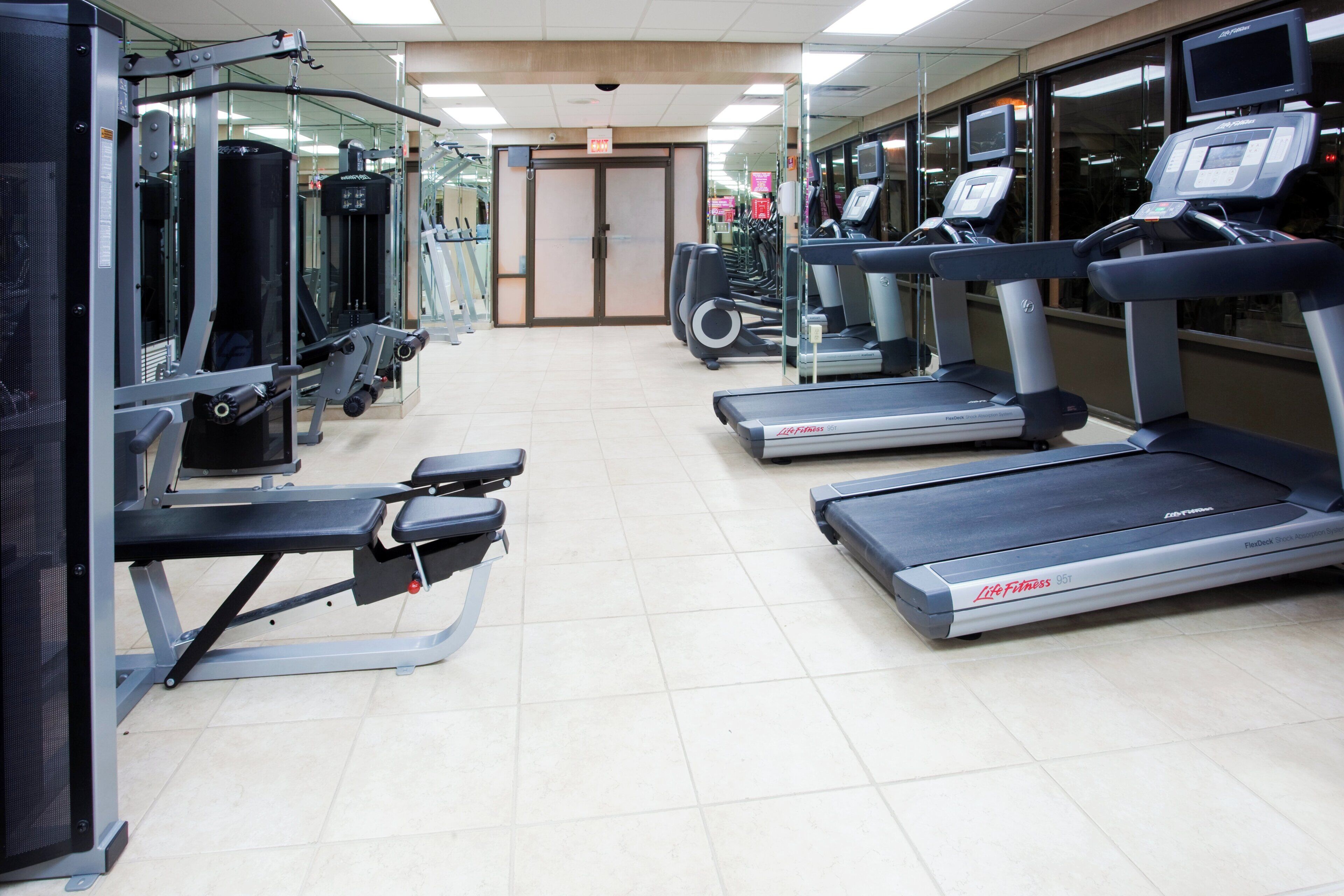 Un gimnasio con cintas de correr, máquinas de pesas y equipo de ejercicio.