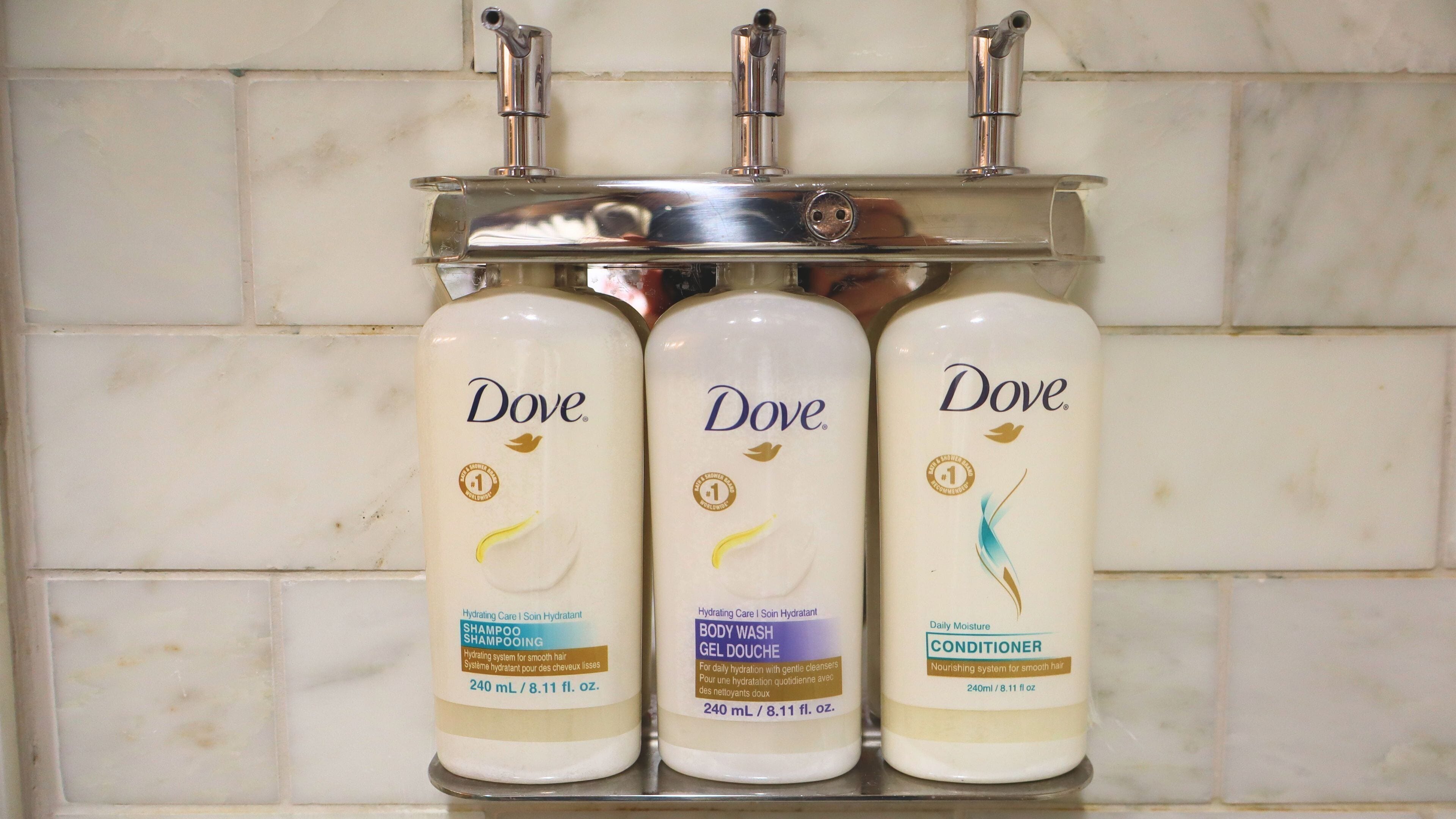 Three Dove product bottles on a bathroom shelf.