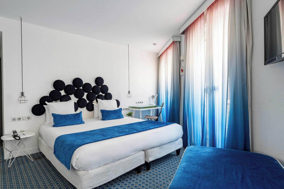 Une chambre d’hôtel moderne avec un grand lit, un bureau et une chaise.