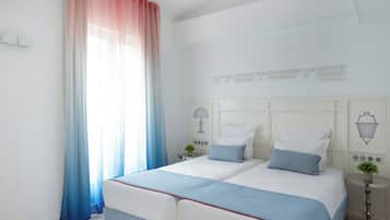 A bedroom with a bed, two bedside tables, a wall-mounted lamp, and a window with sheer curtains.