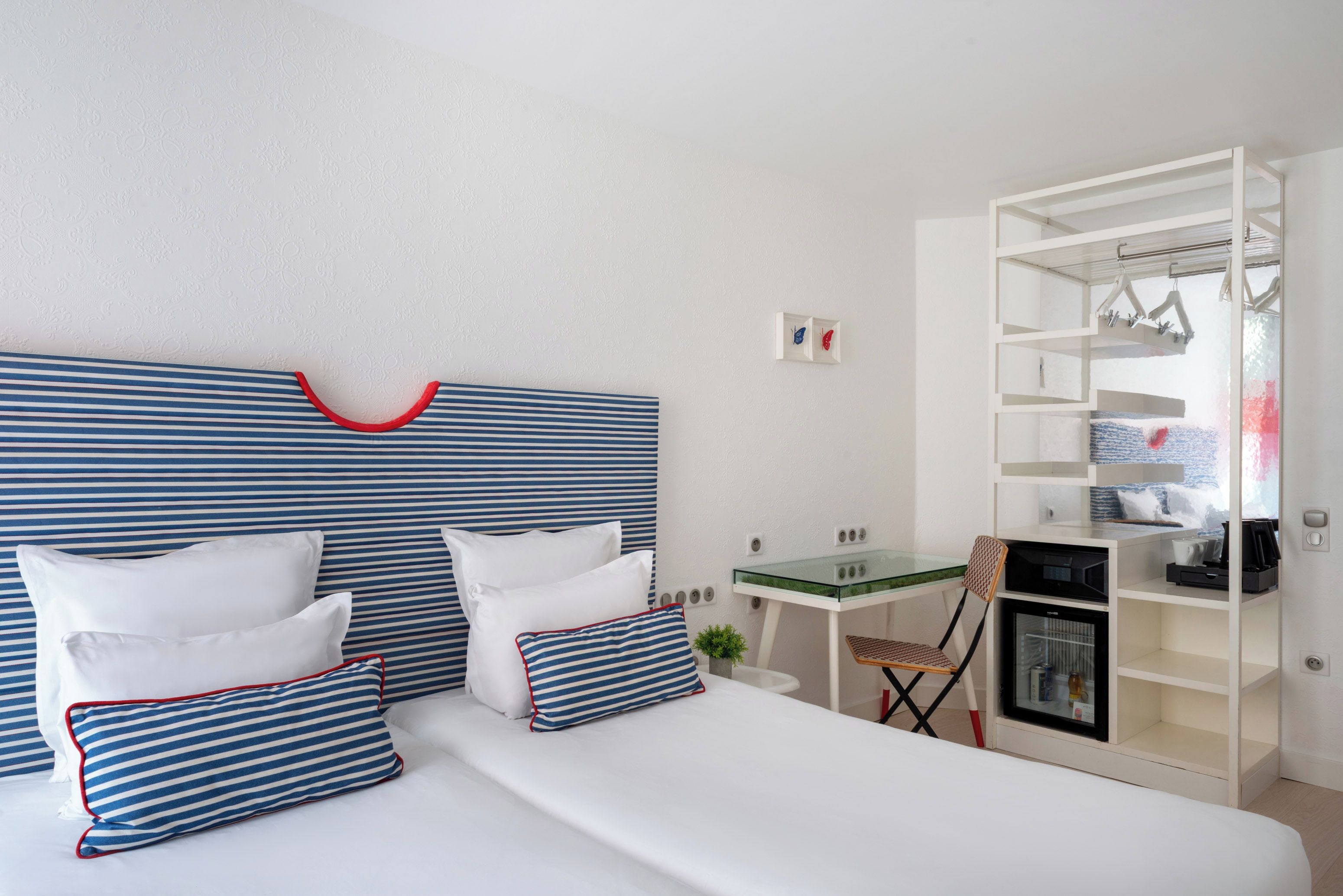 Une chambre d’hôtel équipée d’un lit, d’oreillers, d’un bureau, d’une chaise, d’un petit réfrigérateur et d’une armoire.