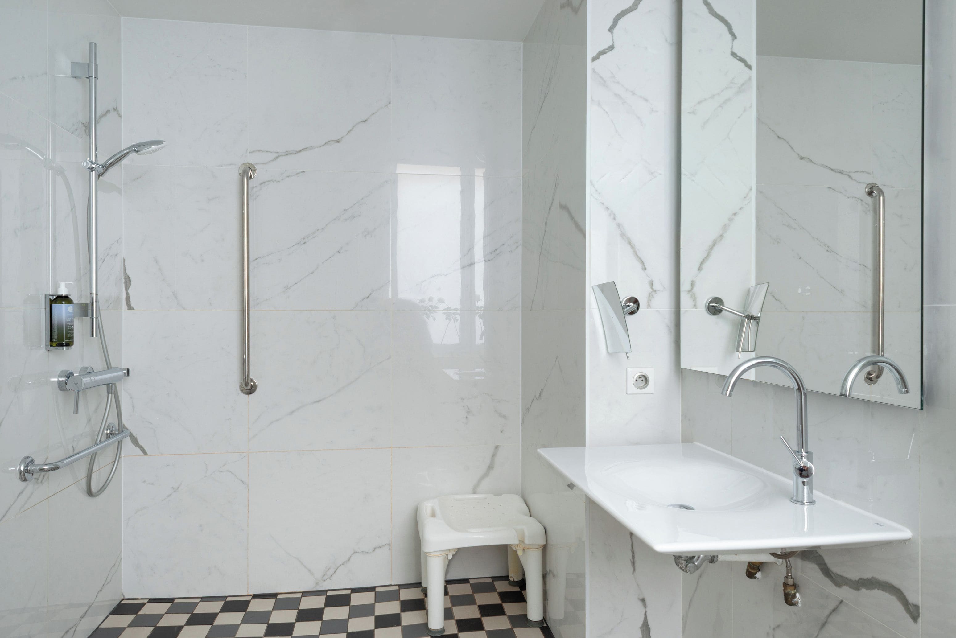 A modern bathroom with a white sink, a handheld showerhead, and a toilet.