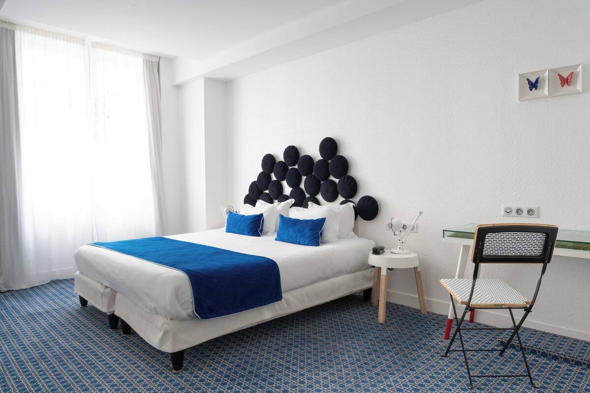 Une chambre d’hôtel bien rangée, avec un lit, une chaise et une petite table.
