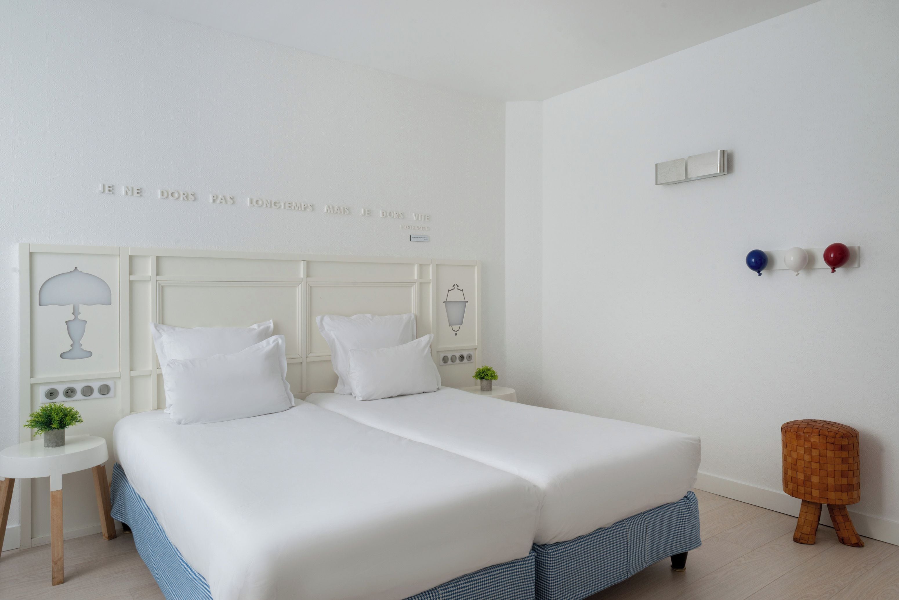 A modern bedroom with a large bed, bedside tables, and a wall-mounted light fixture.