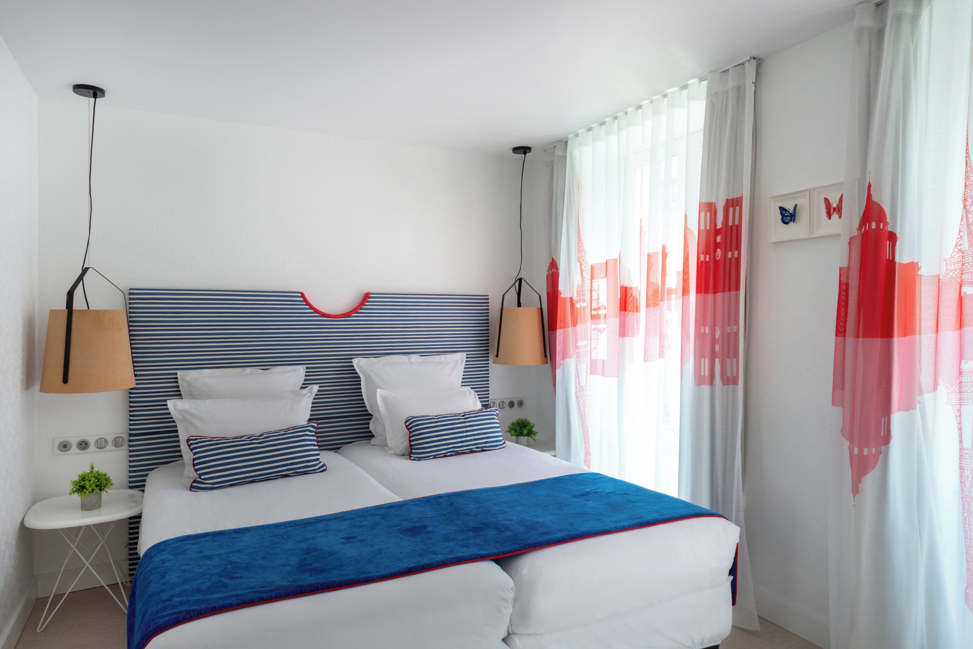 Quarto moderno com cama grande, cabeceira listrada e detalhes em azul.