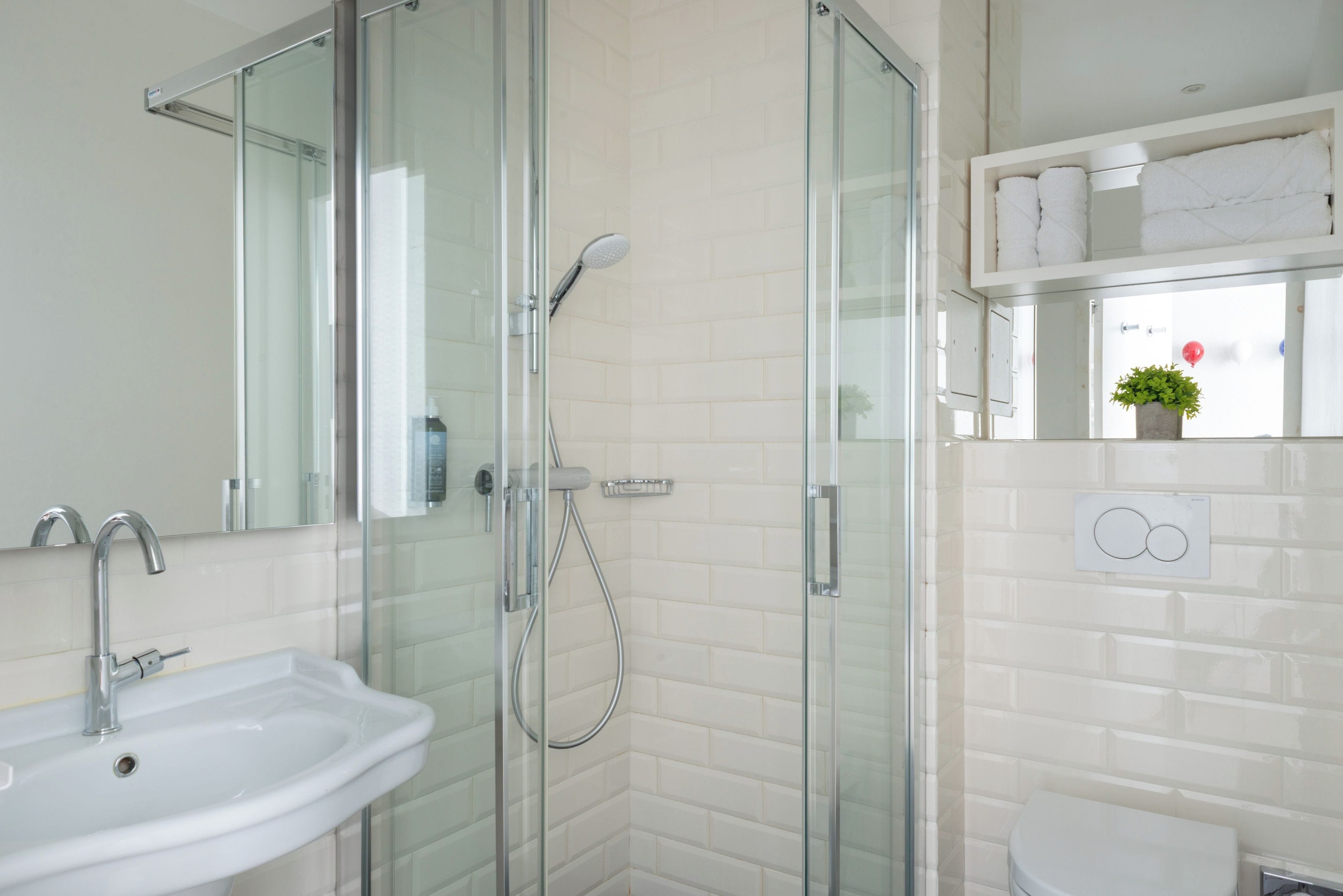 A modern bathroom with a glass-enclosed shower, a white sink, and a toilet.