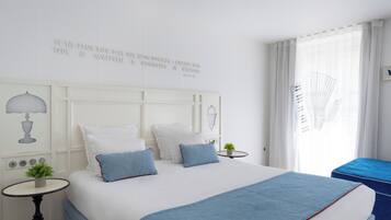 A hotel room with a large bed, two bedside tables, a small table with a plant, and a window with curtains.
