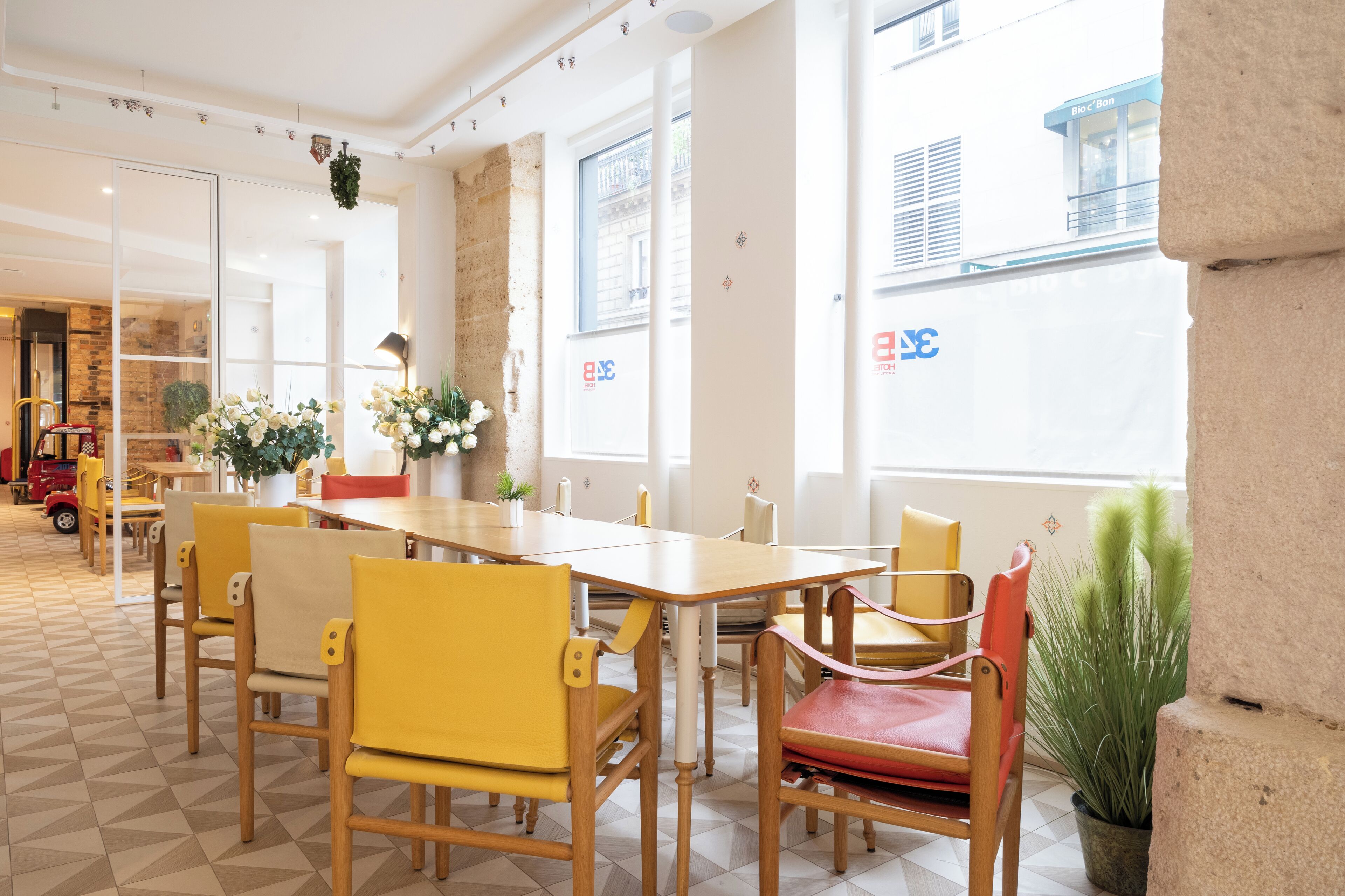 Una habitación luminosa y bien iluminada, con una mesa grande y sillas, una planta en maceta y vistas al exterior a través de amplios ventanales.