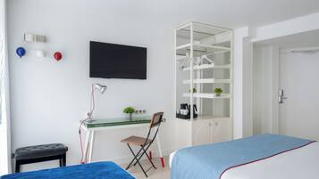 A bedroom with a bed, a desk with a chair, a television, and a wardrobe.