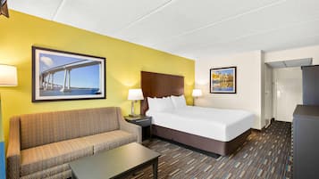A hotel room with a bed, a sofa, a table, and two lamps.