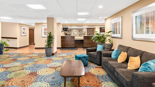 A hotel lobby with a patterned carpet, a reception desk, a sofa with cushions, and potted plants. - Comfort Inn Chula Vista San Diego South (Chula Vista)
