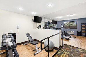 Et fitnesscenter med træningsudstyr, løbebånd og spinningcykel.