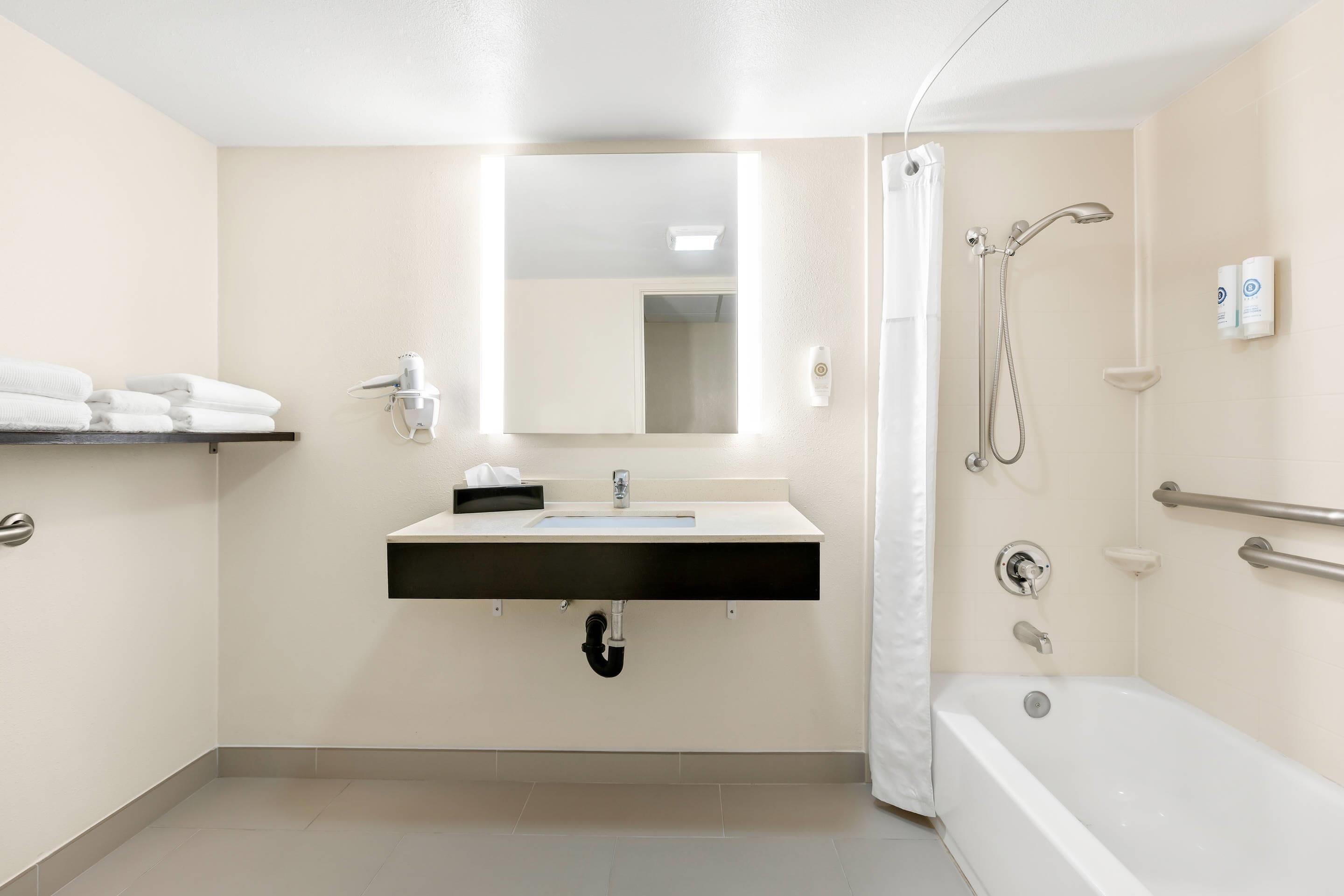 Un baño moderno con lavabo, espejo, ducha y toallero.