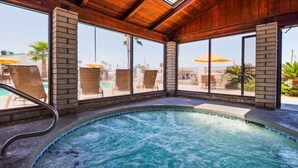 Een hottub met uitzicht op een zwembad en ligbedden.