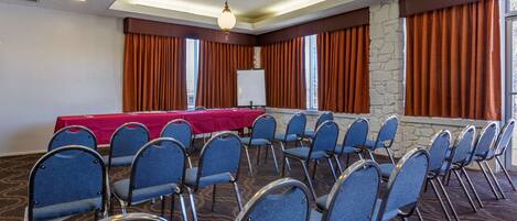 A conference room with a long table, blue chairs, and a stone accent wall.