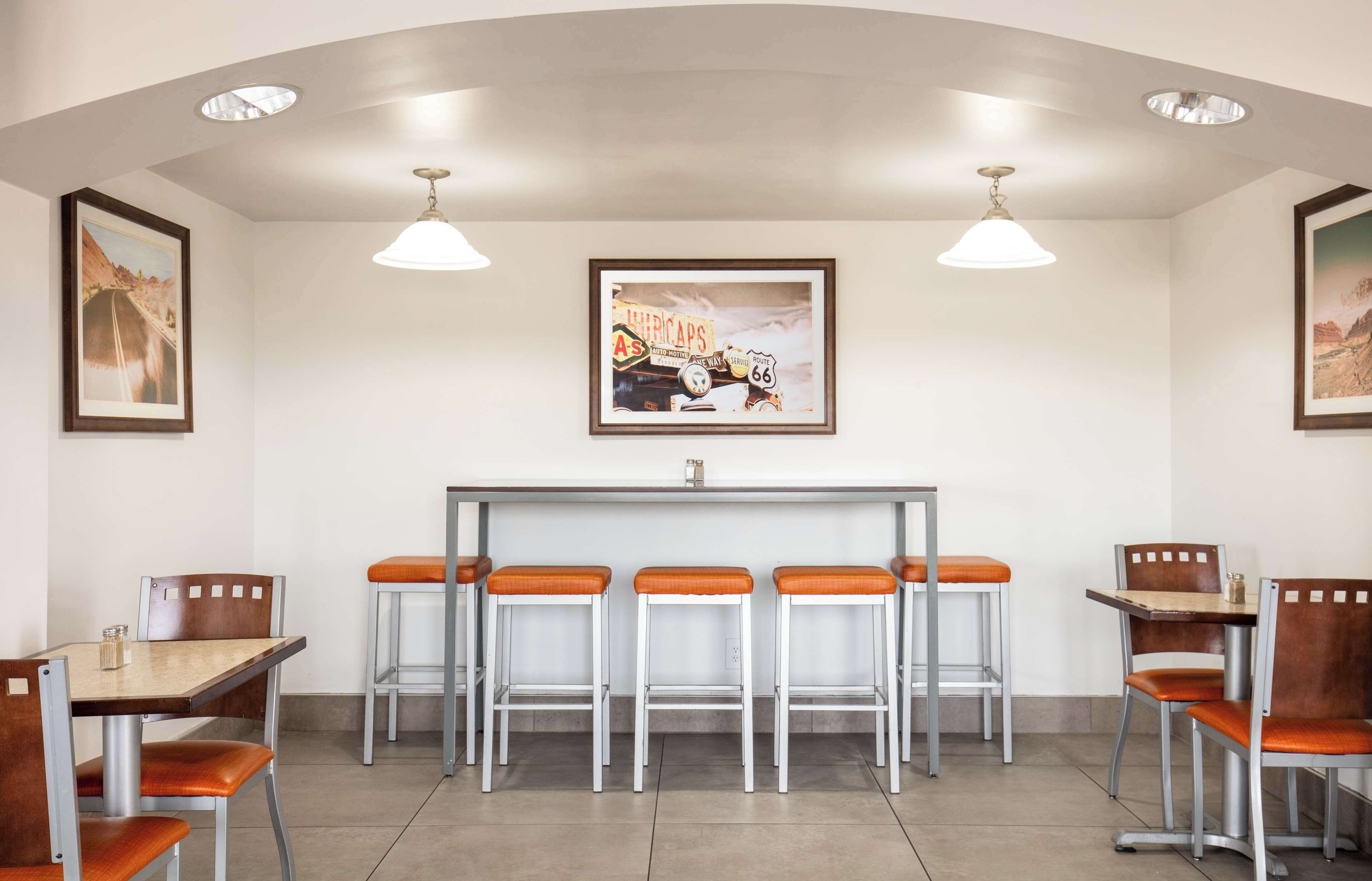 Un restaurant avec un comptoir, des tabourets de bar et des tableaux encadrés aux murs.