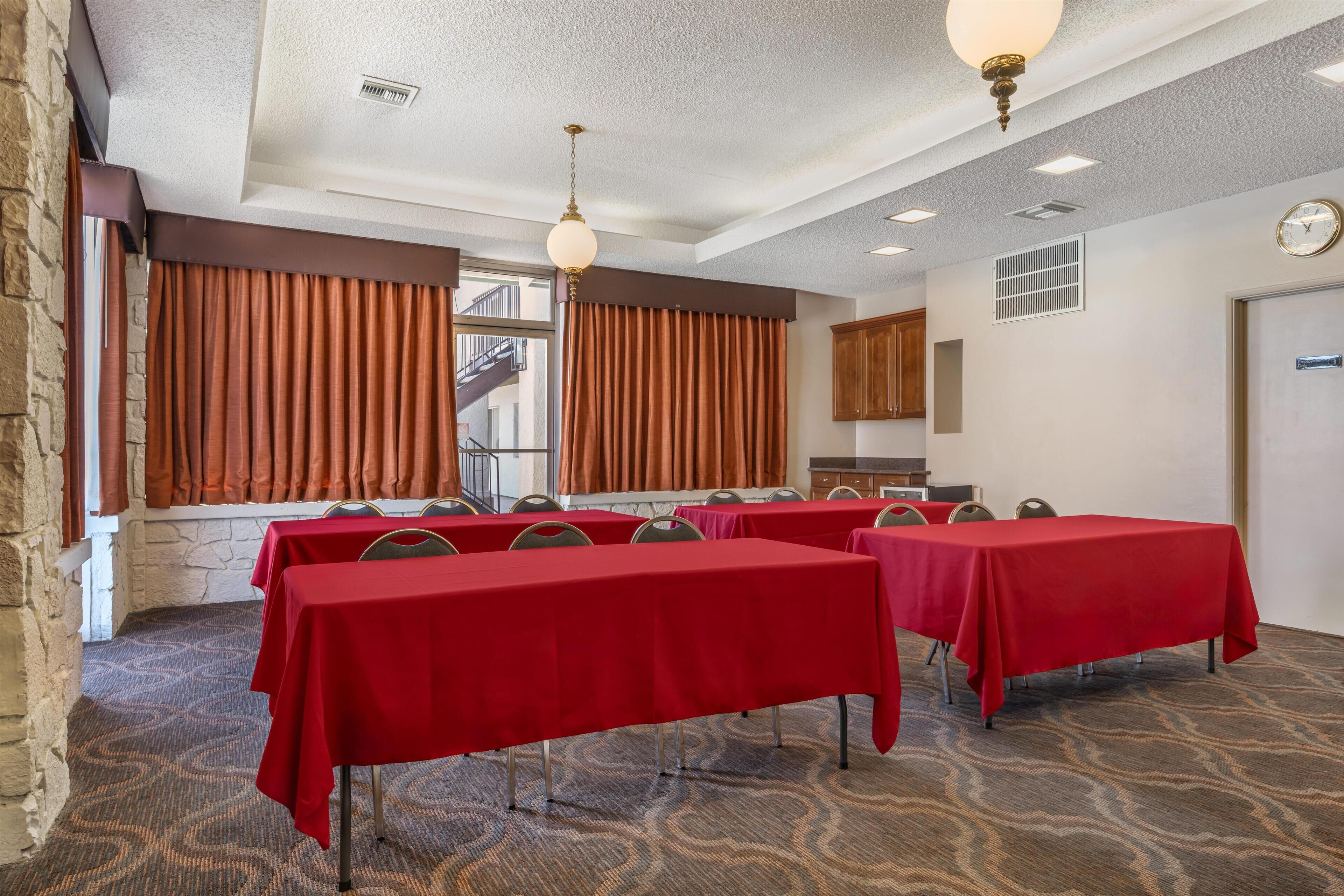 A conference room with red tables, a stone wall, and a view of the outside.