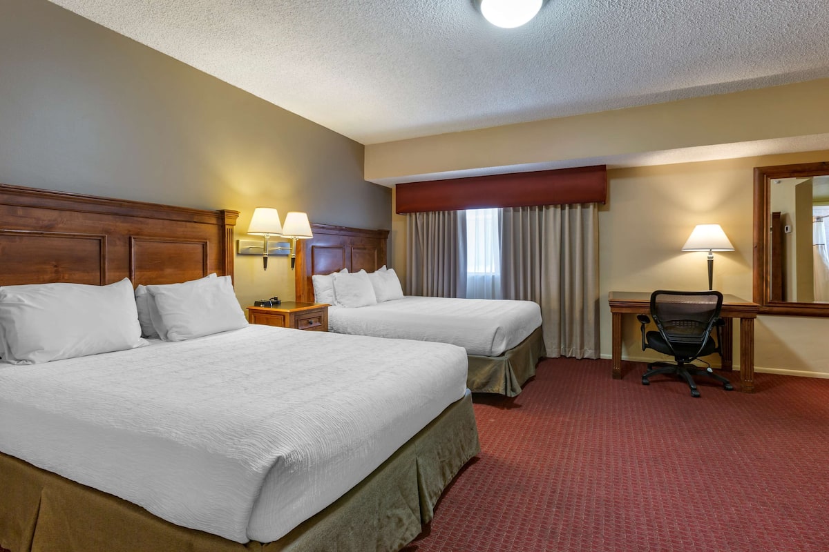 A hotel room with two beds, a desk, and a chair.